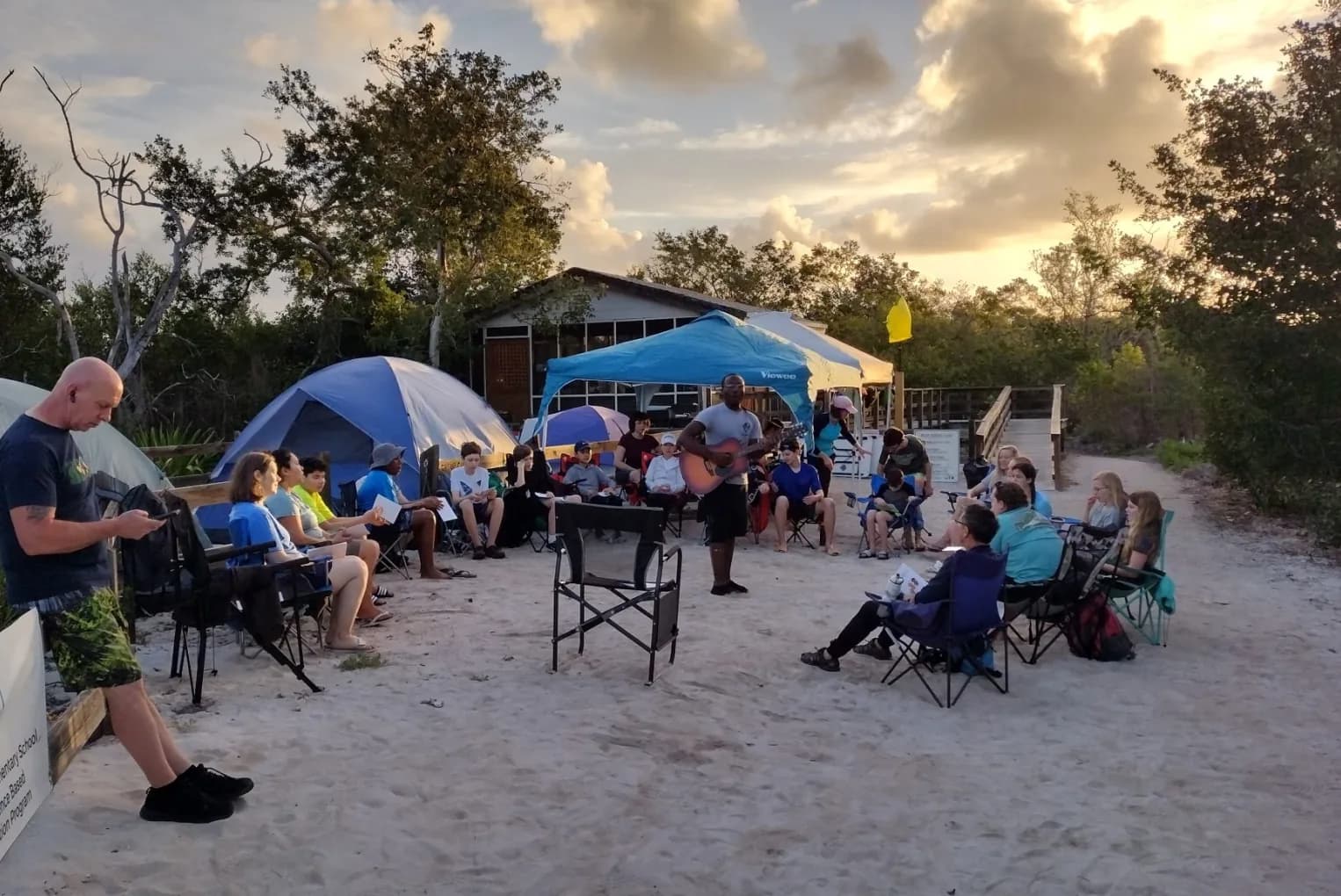 Students and teachers gather for evening worship at a beach campsite