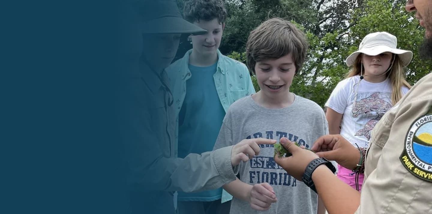 Students examine a plant with a park ranger on a class trip to Florida