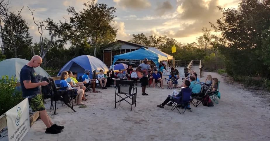 Students gather for evening worship at a beach campsite
