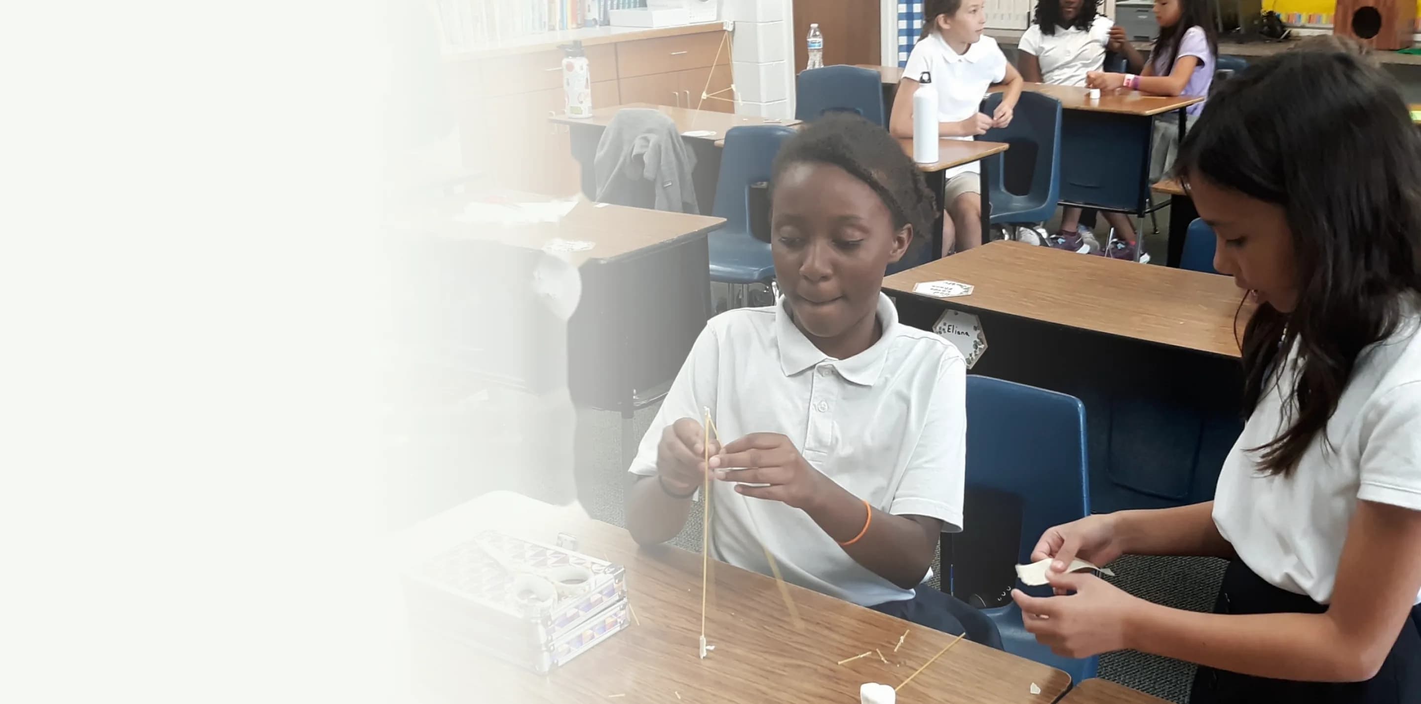 Students build a spaghetti tower together in a Village classroom